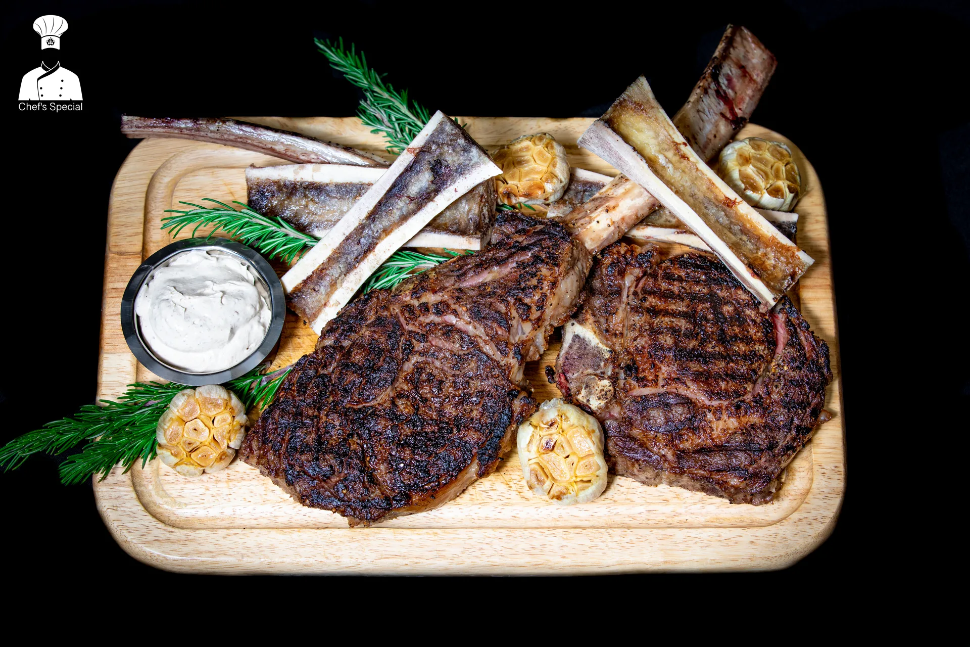 Tomahawk steak on wood board with bone marrow and herb dip